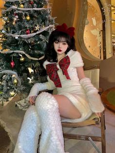 a woman sitting on a chair in front of a christmas tree wearing stockings and boots