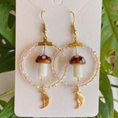 a pair of hoop earrings with beads and mushrooms on the inside, hanging from a card