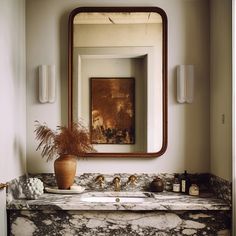 a bathroom sink with a mirror above it and a vase on the counter next to it