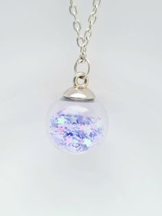 These pretty glass necklace, sparkle pendant, in a variety of colours, would make a fantastic present for birthday gift for mother, daughter, neice or gift for her.  Why not treat yourself to a self gift. sale. These confetti bauble pendants are filled with glitter, crystals or stars with silver plated finish. The colours available are pink, dark pink, green, purple, gold, multicolored, silver, orange and lilac. The necklace length is 16 or 18 inches silver plated. The following items cannot be Magical Silver Crystal Necklace For Gift, Magical Silver Charm Necklaces As Gift, Magical Silver Charm Necklaces For Gift, Silver Crystal Necklace For Gift, Silver Crystal Necklace For Gift With Magical Style, Handmade Star Necklaces For Party, Iridescent Glass Necklaces As Gifts, Iridescent Pendant Crystal Necklace For Gift, Iridescent Crystal Pendant Necklace For Gift