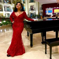 a woman in a red dress standing next to a piano