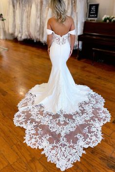 a woman in a white wedding dress standing on a wooden floor with her back to the camera