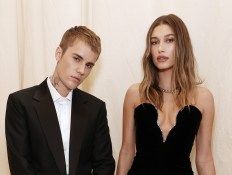 two people standing next to each other in front of a white wall wearing suits and ties