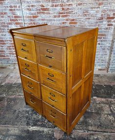 an old wooden chest of drawers in front of a brick wall