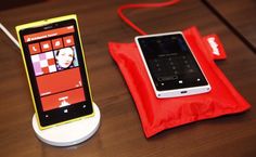 a cell phone sitting on top of a wooden table next to a red pouch with a woman's face on it