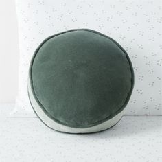 a green round pillow sitting on top of a bed