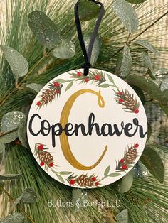 a christmas ornament hanging from a pine tree with the letter c on it