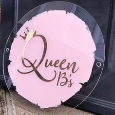 a glass sign with the words queen b's written on it and a gold crown