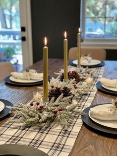 the table is set for christmas dinner with pine cones and candles