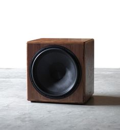 a wooden speaker sitting on top of a white floor next to a black and gray wall