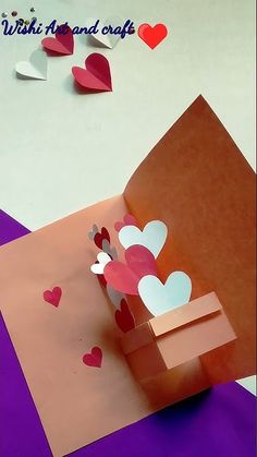 an origami box with hearts on it and paper cut out to look like a house