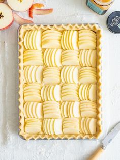 an apple tart with sliced apples on the side next to a knife and butter