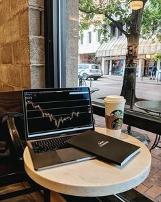 a laptop computer sitting on top of a white table next to a cup of coffee