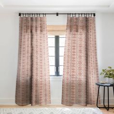 a living room with white walls and beige curtains on the windowsill, along with a rug