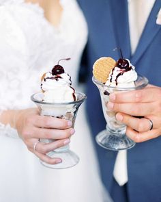 a bride and groom holding ice cream sundaes with cherries on top in their hands