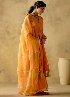 Features a tangerine front open silk anarkali embellished with zari & patra work, finished with gota lace & button detailing on the front. Completed with a matching sharara with lace detailing and an embellished dupatta. Composition : Anarkali & Sharara: Chanderi Silk Lined with Mul Cotton, Dupatta: Organza Care: Dry Clean Only and Vacuum Storage All products can be customised for sleeves, length of blouse and neck design Delivery : 3-4 weeks as the product is hand crafted. Check Size Guide or choose MySize for free customisation (All Sizes above XL can be made at 15% additional cost) For more information and sizes please contact fabiliciousfashion@gmail.com or visit our Copenhagen studio. Orange Anarkali, Silk Anarkali, Vacuum Storage, Cotton Dupatta, Lace Button, Sharara Set, Lace Embroidery, Anarkali, Aza Fashion