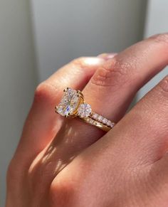 a woman's hand holding a yellow and white diamond ring with two diamonds on it