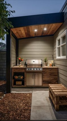 an outdoor kitchen is lit up at night with lights on the ceiling and grill area