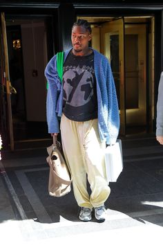 a man walking down the street with his hand in his pocket and holding two bags