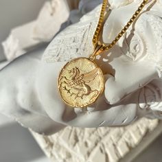 a gold necklace with a coin on it sitting next to a bust of a man