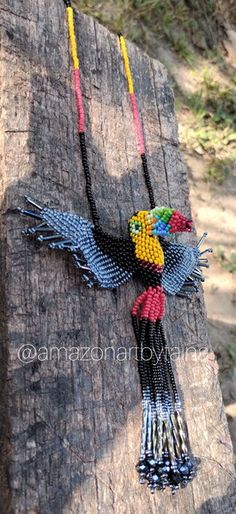 a necklace made out of beads on a piece of wood with a bird hanging from it's side