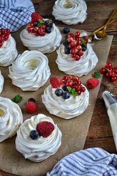 cupcakes with white frosting, berries and blueberries are on a cutting board