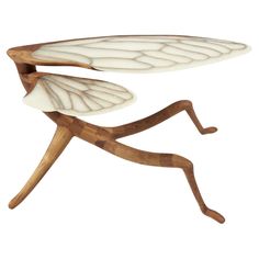 a wooden table with a white insect on it's leg and legs in the shape of a leaf