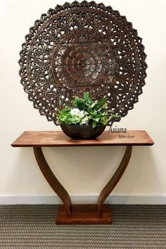 a wooden table topped with a bowl filled with flowers next to a wall mounted planter