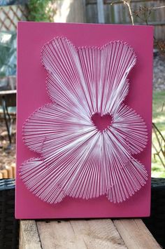 a pink card with white string art in the shape of a flower on top of it