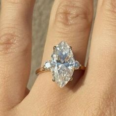 a woman's hand with a ring on it and an oval shaped diamond in the middle