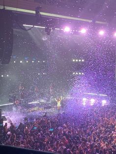 a large group of people at a concert with confetti falling from the ceiling