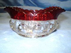 a red glass bowl sitting on top of a white table