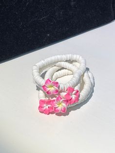 This is a white beaded bracelet with a Hawaiian flower in the center. There are 7 colors of the flower. the colors include pink and yellow, pink and white, magenta and yellow, dark purple and yellow, green and yellow, blue and yellow, white and yellow. Each bracelet is about 6-7 inches in circumference and the bracelets are stretchy. Bohemian Flower Bracelets For Vacation, White Round Beads Bracelet For Vacation, White Round Beads Bracelets For Vacation, White Beaded Bracelets For Vacation, White Round Beaded Bracelets For Vacation, White Round Bead Bracelets For Vacation, Adjustable White Jewelry With Flower Decoration, Handmade White Stretch Bracelet For Vacation, Pink Flower-shaped Jewelry For Vacation