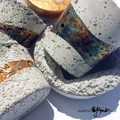 four cement cups and saucers sitting on top of a white plate with rusted edges