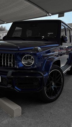 a blue jeep parked under a canopy in a parking lot