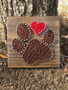 a wooden sign with string art on it that says love is in the shape of a dog's paw