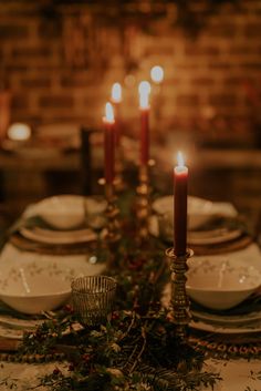 the table is set with candles and dishes for christmas dinner guests to sit down at