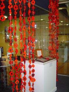 red flowers are hanging from the glass display case