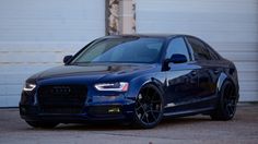 a blue car parked in front of a garage