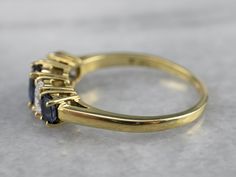 This is a timeless and attractive design for a wedding band, stacking ring, or even an engagement piece. The sapphires are deep blue, classically cut gems, perfectly matched in hue and graduating in size. Interspersed between the sapphires are brilliant oval-cut diamonds, adding some sparkle and fire to this lovely piece! Metal: 18K Yellow Gold Gem: Sapphire Gem Measurements: 6.0 x 4.3 mm, Oval Accents: 2 Sapphires, 2 Diamonds totaling .54 Carats, F in Color, VVS in Clarity Ring Size: 8 Marks: " Formal Fine Jewelry Stackable Three-stone Rings, Classic Sapphire Ring With Diamond Half Eternity, Timeless Sapphire Anniversary Ring, Timeless Sapphire Ring With Diamond Baguette Cut, Timeless Sapphire Baguette Cut Ring With Prong Setting, Timeless Sapphire Baguette Cut Ring With Diamond Details, Classic Sapphire Ring With Baguette Cut, Timeless Sapphire Baguette Cut Ring, Timeless Sapphire Ring With Round Band