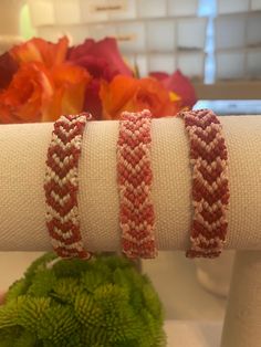 three bracelets are sitting on top of each other in front of a vase with flowers