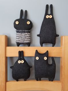 three black stuffed animals are hanging on a wooden shelf with buttons in the shape of cats