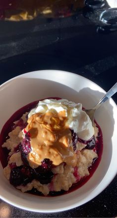 a white bowl filled with oatmeal and fruit covered in syrup on top of a table