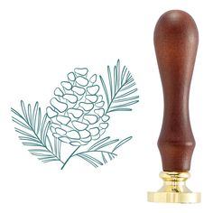 a wooden stamp with a pine cone and evergreen needles on it, next to a gold base