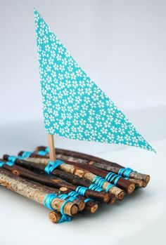 there is a small boat made out of wood and sticks with blue ribbons on it