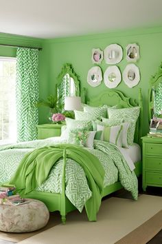 a bedroom decorated in green and white with lots of mirrors on the wall above the bed