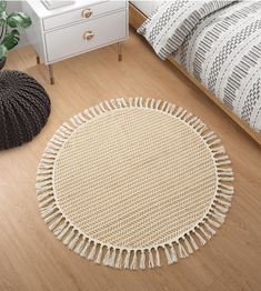 a round rug with tassels is on the floor next to a white bed