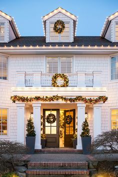 a large white house with wreaths and lights on the front door