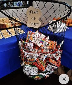 a basket full of chips sitting on top of a table next to a sign that says fish n chips