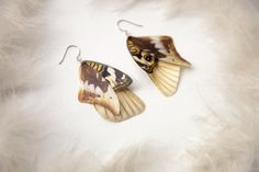 a pair of butterfly shaped earrings sitting on top of a white fur covered surface,